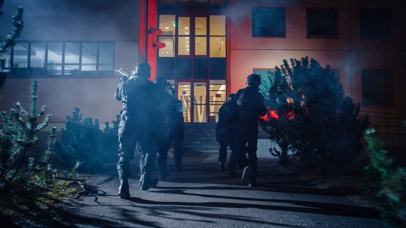 Stock photo of SWAT officers running in formation into a building.