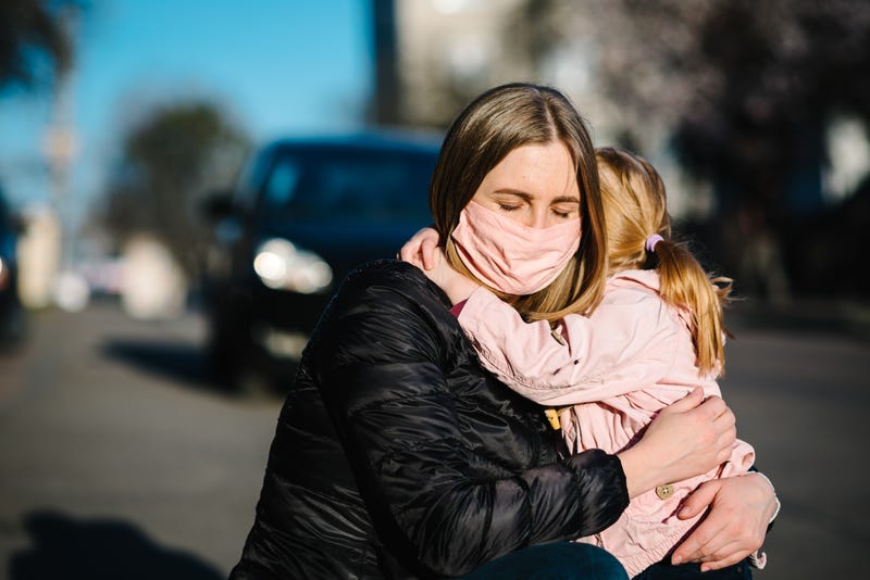 woman in facemask hugs child
