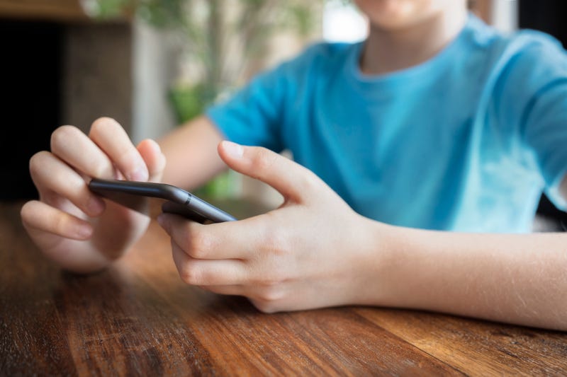 A young boy uses a cellphone.