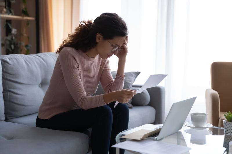 upset woman looks at piece of paper