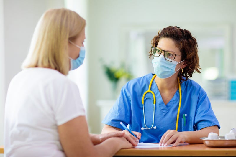 doctora con una paciente, ambas usando mascarilla