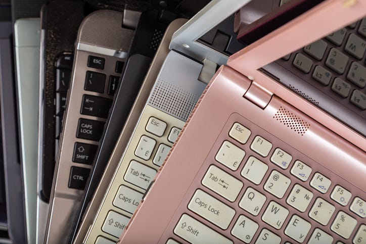 Stack of used laptops in different colors and models