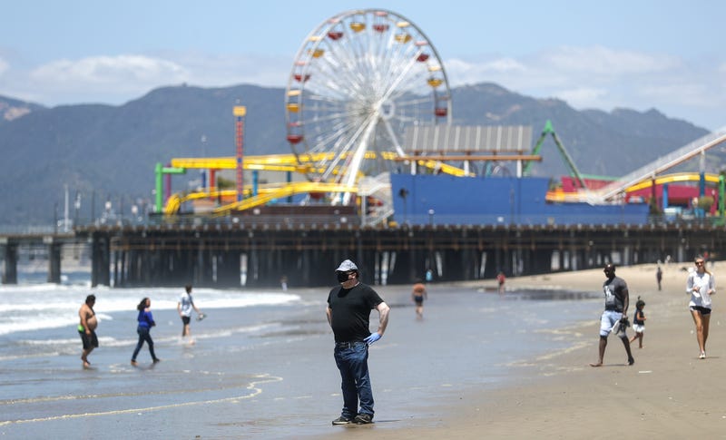 A man wears a face mask and gloves on Santa Monica beach on the day Los Angeles County reopened its beaches, which had been closed due the coronavirus pandemic, on May 13, 2020 in Santa Monica, California.