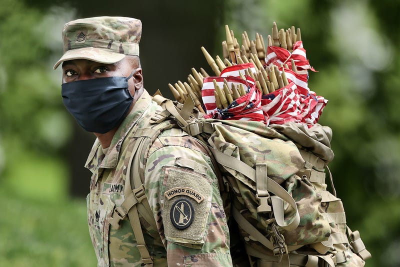 Wearing face masks to reduce the risk of spreading the novel coronavirus, a soldier from the 3rd Infantry Regiment, or the "Old Guard," works to place U.S. flags in front of every grave site ahead of the Memorial Day weekend in Arlington National Cemetery on May 21, 2020 in Arlington, Virginia. Traditionally known as "Flags-In," soldiers place small flags in front of more than 228,000 headstones and at the bottom of about 7,000 niche rows in the cemetery's Columbarium Courts and Niche Wall . (Photo by Chip Somodevilla/Getty Images)