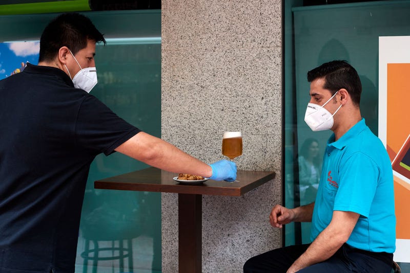 Aldovladimir Trigo serves a beer to a client at the Casa Dani restaurant on May 25, 2020 in Madrid, Spain. Some parts of Spain have entered the so-called "Phase One" or "Phase Two" transitions from its coronavirus lockdown, allowing many shops to reopen as well as restaurants who serve customers outdoors. Locations that were harder hit by the coronavirus (COVID-19), such as Madrid and Barcelona, remain in a stricter quarantine.