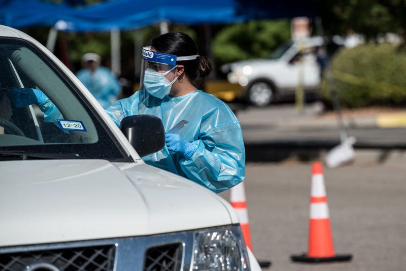 A nurse conducts a coronavirus test at a newly opened mega drive-thru site at El Paso Community College Valle Verde campus on July 21, 2020 in El Paso, Texas. As coronavirus deaths surge past 4000 in Texas, overwhelmed hospitals are being forced to plan for extra refrigerated storage to hold deceased patients.
