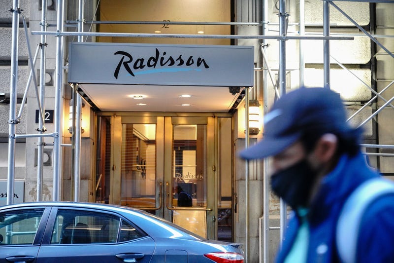 A person wearing a face mask walks past a former Radisson Hotel at Wall street that were converted to homeless shelter.