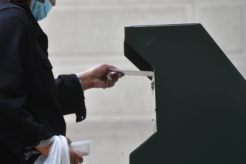 A woman deposits a ballot in an official ballot drop box outside of Philadelphia City Hall