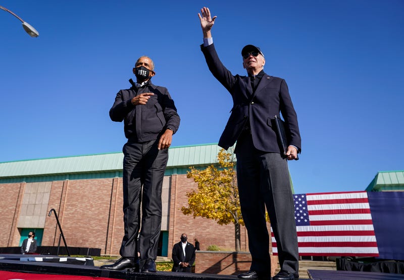 Former U.S. President Barack Obama and Democratic presidential nominee Joe Biden wave to the crowd at the end of a drive-in campaign rally at Northwestern High School on October 31, 2020 in Flint, Michigan.
