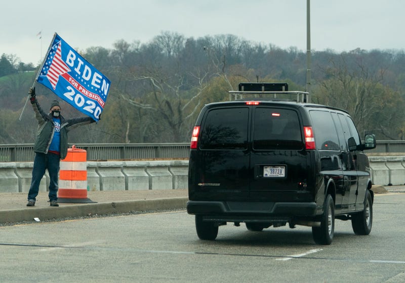 A protester holds up a sign in support of US President-elect Joe Biden, as the motorcade with US President Donald Trump passes in Washington, DC on November 26, 2020.