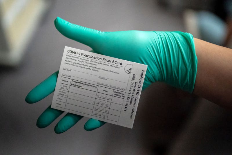 A healthcare worker displays a COVID-19 vaccine record card