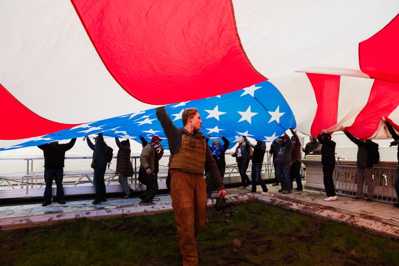 A group of pro-Trump protesters raise a giant America Flag on the West grounds of the Capitol Building on January 6, 2021 in Washington, DC. A pro-Trump mob stormed the Capitol earlier, breaking windows and clashing with police officers. Trump supporters gathered in the nation's capital today to protest the ratification of President-elect Joe Biden's Electoral College victory over President Trump in the 2020 election. (Photo by Jon Cherry/Getty Images)