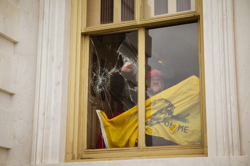 A rioter gestures from inside a broken Capitol window during insurrection by Trump supporters, Jan. 7, 2021.