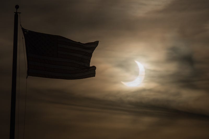 An eclipsed sun rises next to a flag on June 10, 2021 in Scituate, Massachusetts. Northeast states in the U.S. will see a rare eclipsed sunrise, while in other parts of the Northern Hemisphere, this annular eclipse will be seen as a visible thin outer ring of the sun's disk that is not completely covered by the smaller dark disk of the moon, a so-called "ring of fire"