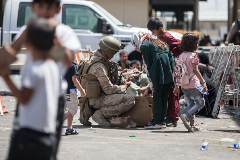 This handout image shows A Marine with Special Purpose Marine Air-Ground Task Force-Crisis Response-Central Command (SPMAGTF-CR-CC) provides meals ready-to-eat to a child during an evacuation at Hamid Karzai International Airport, August 20, 2021 in Kabul, Afghanistan. U.S. service members are assisting the Department of State with an orderly drawdown of designated personnel in Afghanistan. (Photo by Sgt. Samuel Ruiz / U.S. Marine Corps via Getty Images)
