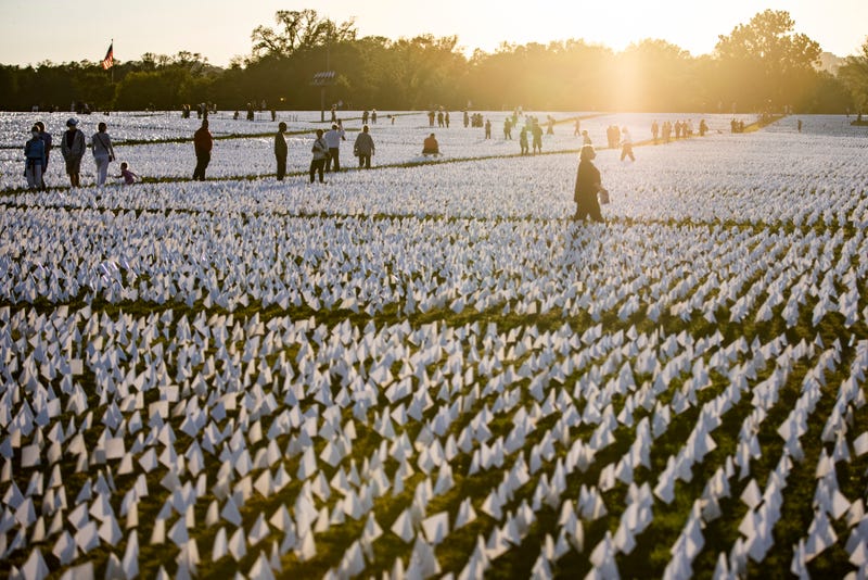 People walk through the flags of the 'In America: Remember' public art installation on the National Mall near the Washington Monument on September 26, 2021 in Washington, DC
