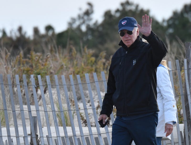 US President Joe Biden waves as he and First Lady Jill Biden walk on Rehoboth Beach, Delaware on November 7, 2021.