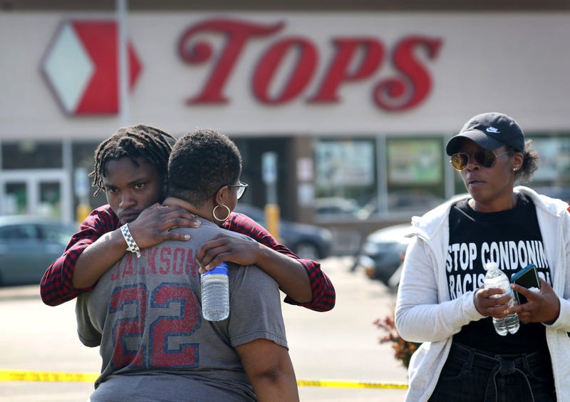 People gathered outside of Tops market embrace on May 15, 2022 in Buffalo, New York. The day before, a gunman opened fire at the store, killing ten people and wounding another three. Suspect Payton Gendron was taken into custody and charged with first degree murder. U.S. Attorney Merrick Garland released a statement, saying the US Department of Justice is investigating the shooting "as a hate crime and an act of racially-motivated violent extremism."