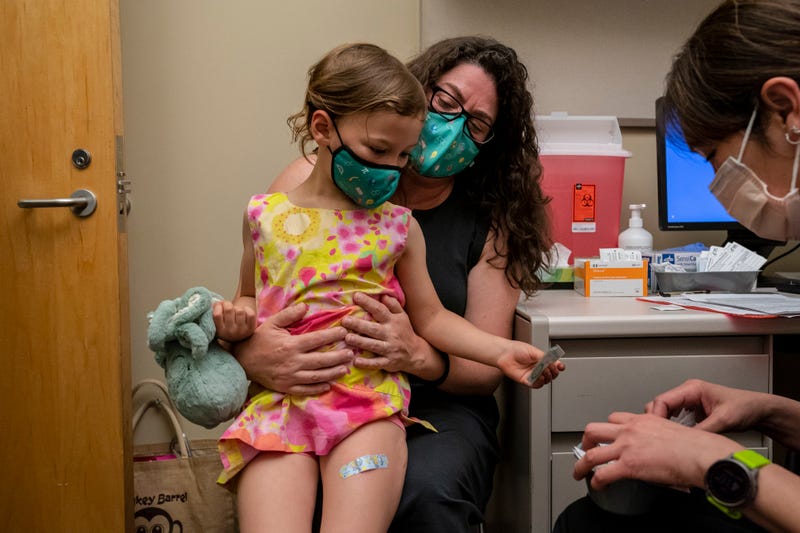 Nora Burlingame, 3, sits on the lap of her mother, Dina Burlingame, and gets a sticker from nurse Luann Majeed after receiving her first dose of the Pfizer Covid-19 vaccination at UW Medical Center - Roosevelt on June 21, 2022 in Seattle, Washington.