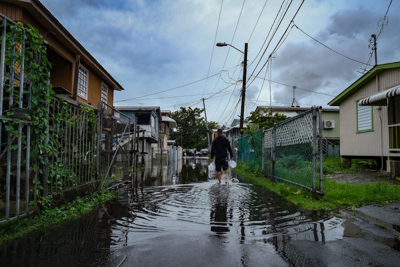 A man walks down a flooded street in the Juana Matos neighborhood of Catano, Puerto Rico, on September 19, 2022, after the passage of Hurricane Fiona.