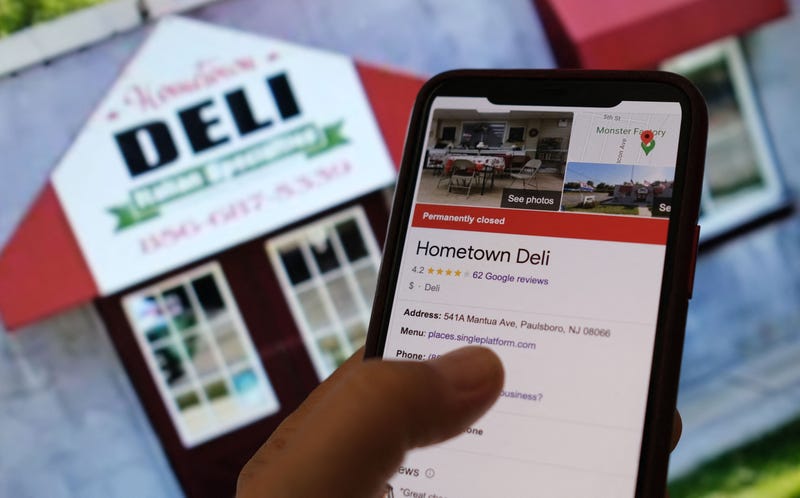 This illustration photo taken on Sept. 26, 2022, in Los Angeles, shows a person checking information online for the now permanently closed Paulsboro, New Jersey's Your Hometown Deli in front of a screen displaying the facade of the restaurant.