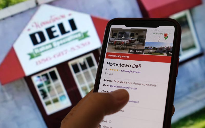 This illustration photo taken on Sept. 26, 2022, in Los Angeles, shows a person checking information online for the now permanently closed Paulsboro, New Jersey's Your Hometown Deli in front of a screen displaying the facade of the restaurant. 