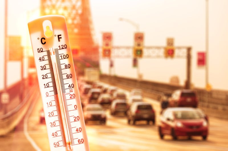Thermometer in front of cars and traffic during heatwave