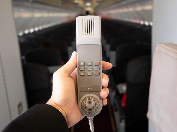 Male cabin crew holding interphone in aircraft cabin