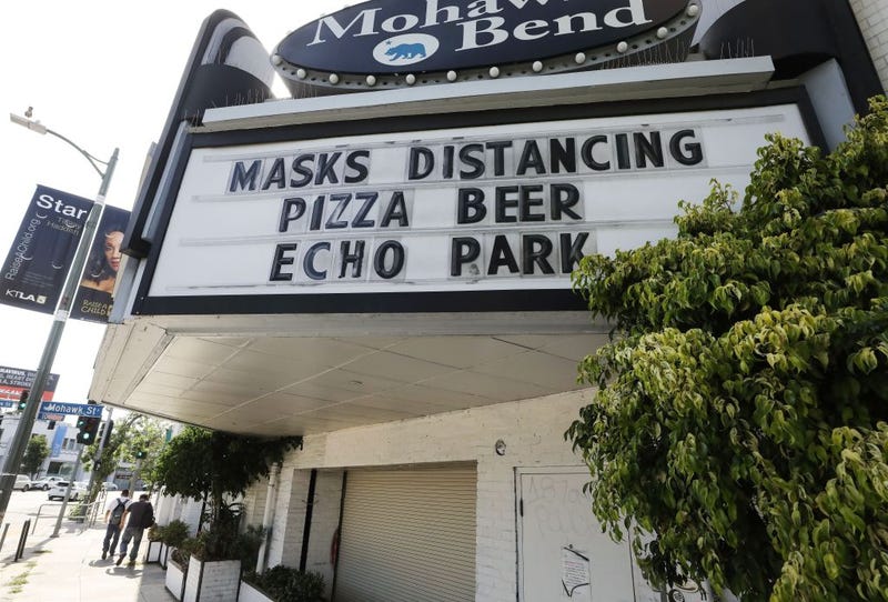 A sign reading 'Masks Distancing Pizza Beer' is displayed above a restaurant and bar on Sunset Boulevard amid the COVID-19 pandemic on June 29, 2020 in Los Angeles, California.