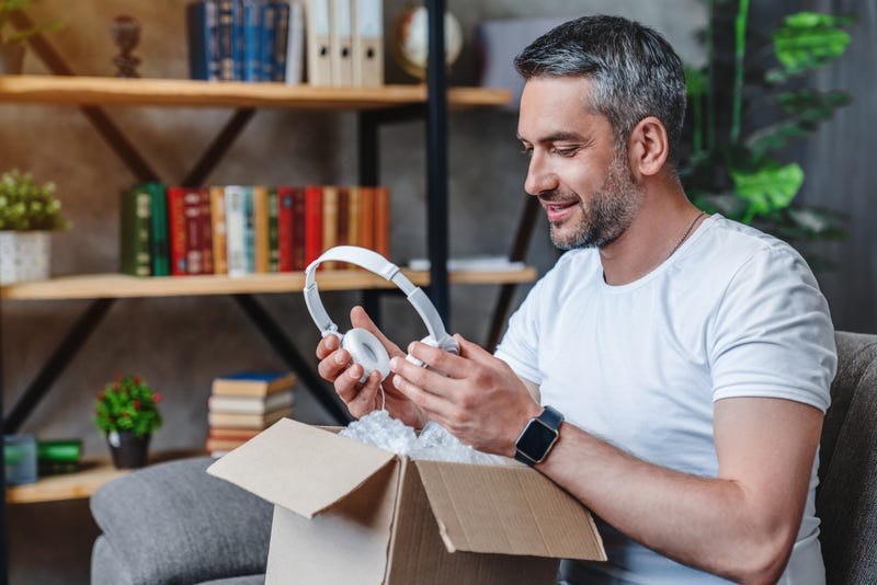 Man pulling headphones out of delivery box.