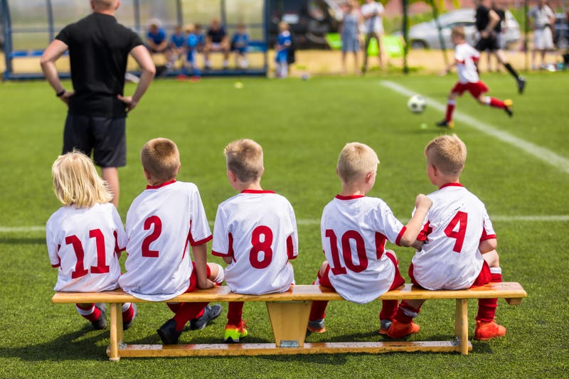 kids in soccer uniforms sittign together on a bench