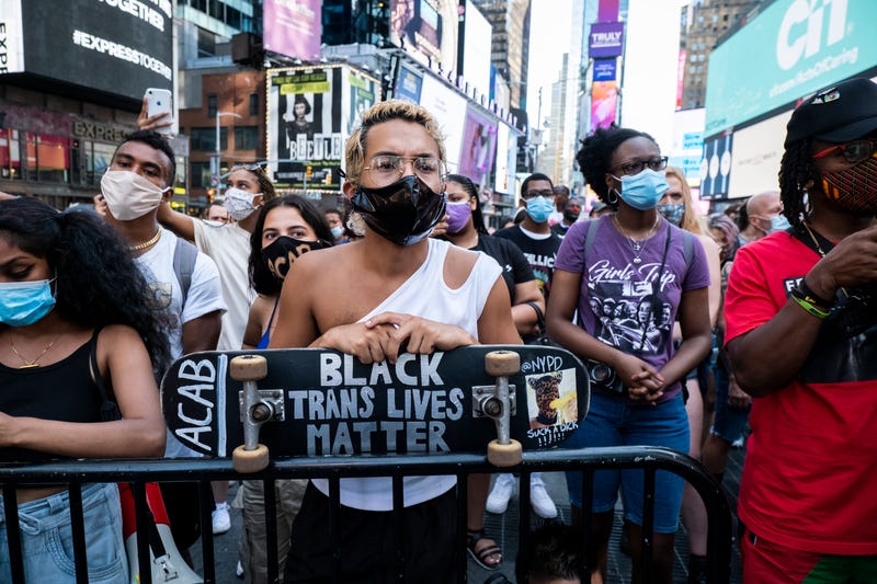 A protester wearing a mask holds a skateboard say, "Black Trans Lives Matter" in Times Square New York in support of Black Women. On July 28, 2020 Nikki Stone a homeless transgender woman was abducted off the streets and taken onto an unmarked van and arrested. This non-violent protest was a March for Black Womxn which started at Times Square and walked through Manhattan. This is days after Portland and other cities have seen federal agents have taken protesters and put into unmarked vehicles while others have been beaten and pepper sprayed. Protesters continue taking to the streets across America and around the world after the killing of George Floyd at the hands of a white police officer Derek Chauvin that was kneeling on his neck during for eight minutes, was caught on video and went viral. During his arrest as Floyd pleaded, "I Can't Breathe". The protest are attempting to give a voice to the need for human rights for African American's and to stop police brutality against people of color. They are also protesting deep-seated racism in America.