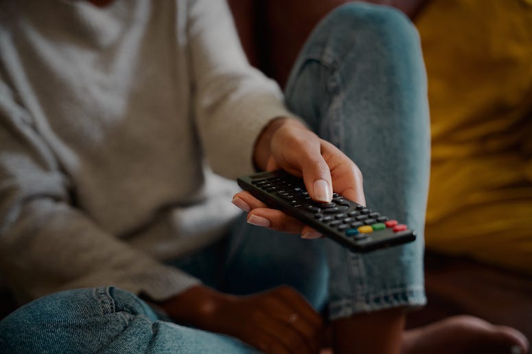 Woman pointing remote control at television