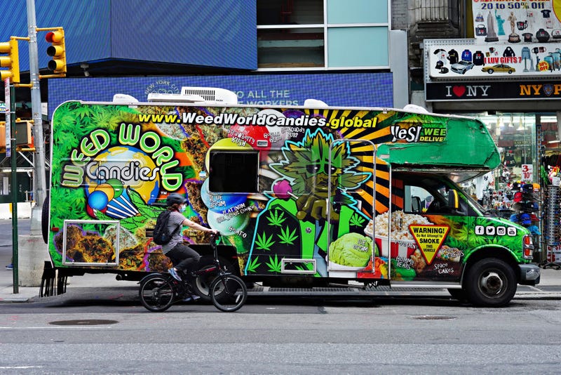 A person wearing a protective mask rides a bike by the Weed World Candies RV as the city continues Phase 4 of re-opening following restrictions imposed to slow the spread of coronavirus on August 21, 2020 in New York City.