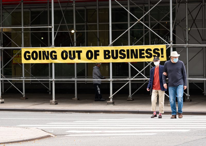 People wearing protective masks walk by a going out of business sign displayed outside Century 21 on the Upper West Side, Sept. 27, 2020, in New York City.