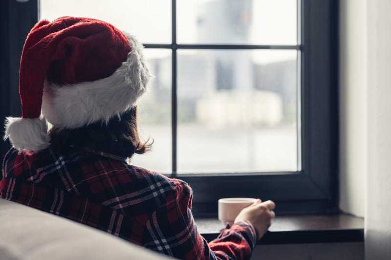 woman in santa hat looking wistfully out the window