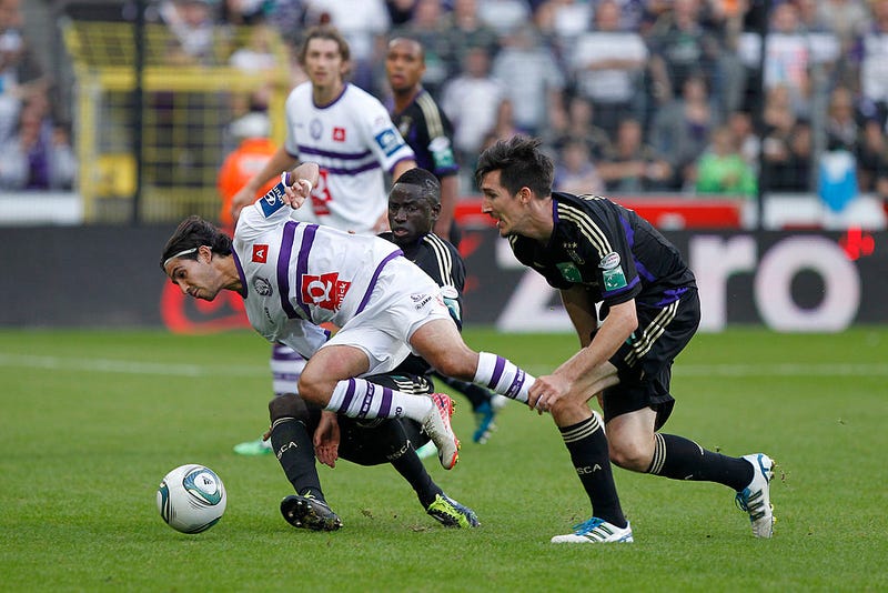 Hernan Losada de K.Beerschot AC es desafiado por Cheikhou Kouyate y Sacha Kljestan de RSC Anderlecht durante el partido de la Jupiler Pro League entre RSC Anderlecht y K.Beerschot AC en el Constant Vanden Stock Stadium el 25 de septiembre de 2011 en Anderlecht, Bélgica.