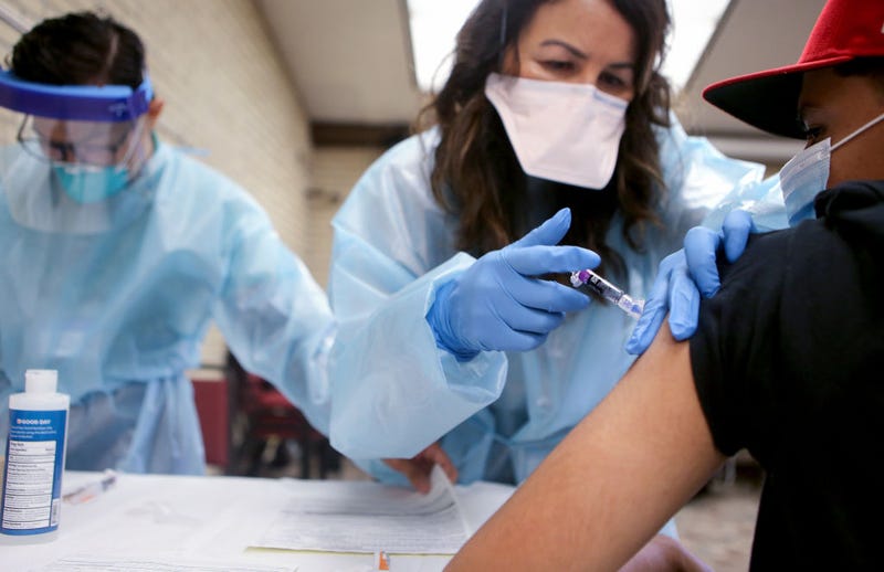 A nurse gives a flu vaccination shot to a young man at a free clinic held at a local library on October 14, 2020 in Lakewood, California.