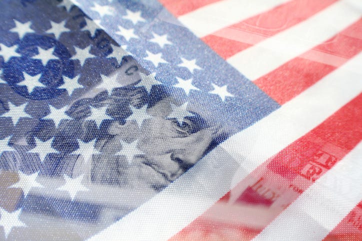 An American flag overlapping a one hundred dollar bill.