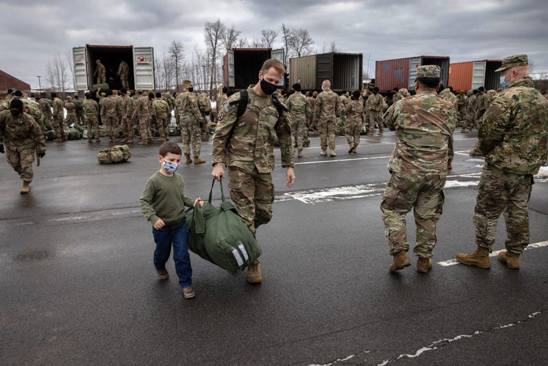 Cal Wasilewski, 5, helps his father U.S. Army Maj. Kurt Wasilewski carry his duffel after soldiers returned home from a 9-month deployment to Afghanistan on December 10, 2020 at Fort Drum, New York, part of the U.S. drawdown from Afghanistan.