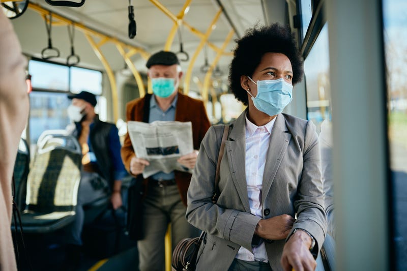 businesswoman wearing face mask and looking through a window while commuting to work by bus.