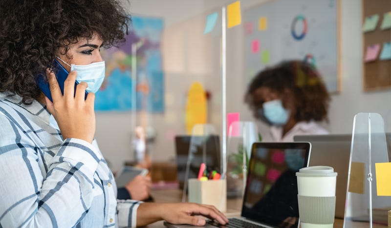 Young people in co-working creative space wearing surgical mask protection and keeping social distance