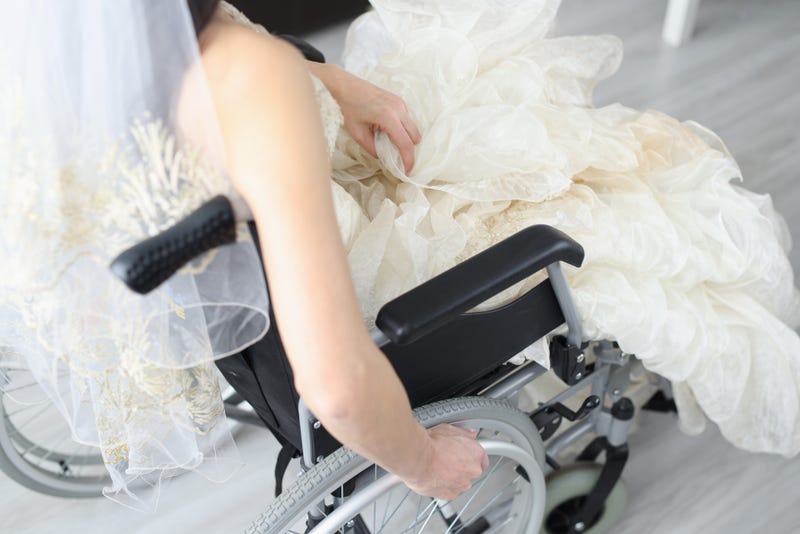 Bride in wedding dress sits in wheelchair