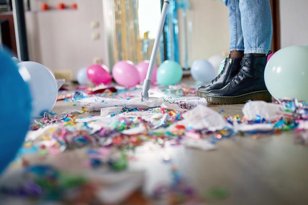 Woman with pushbroom cleaning up after party