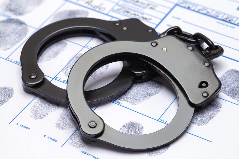 Black metal handcuffs and fingerprints on a chart