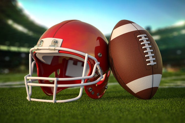 Football ball and helmet on the grass of football arena or stadium