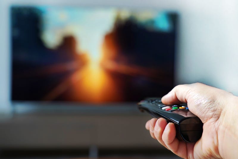 Man pointing remocte control at TV
