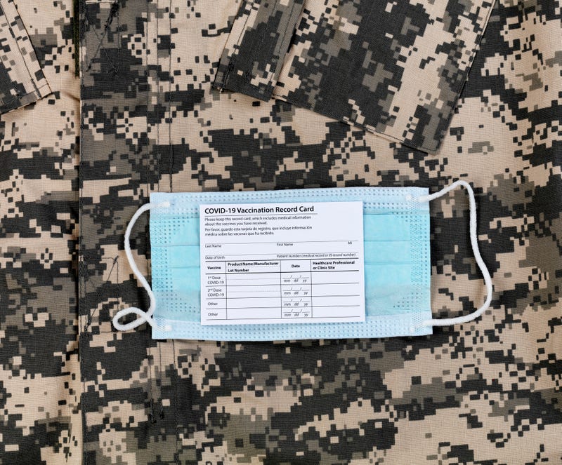 A camouflage shirt, a mask, and a COVID-19 vaccine card.
