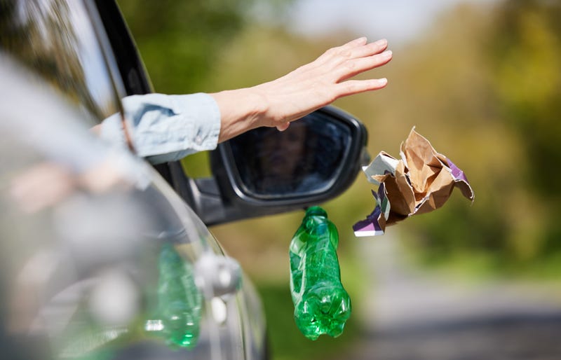 Close Up Of Driver In Car Dropping Trash Out Of Window