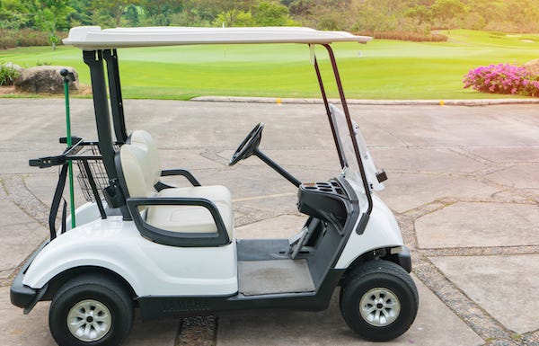 Golf cart parked in front of a golf course